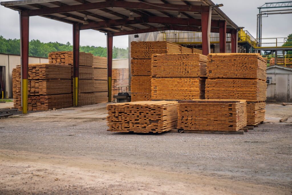 pexels photo 12278566 Stacks of timber planks at an outdoor lumber yard, showcasing construction supplies.