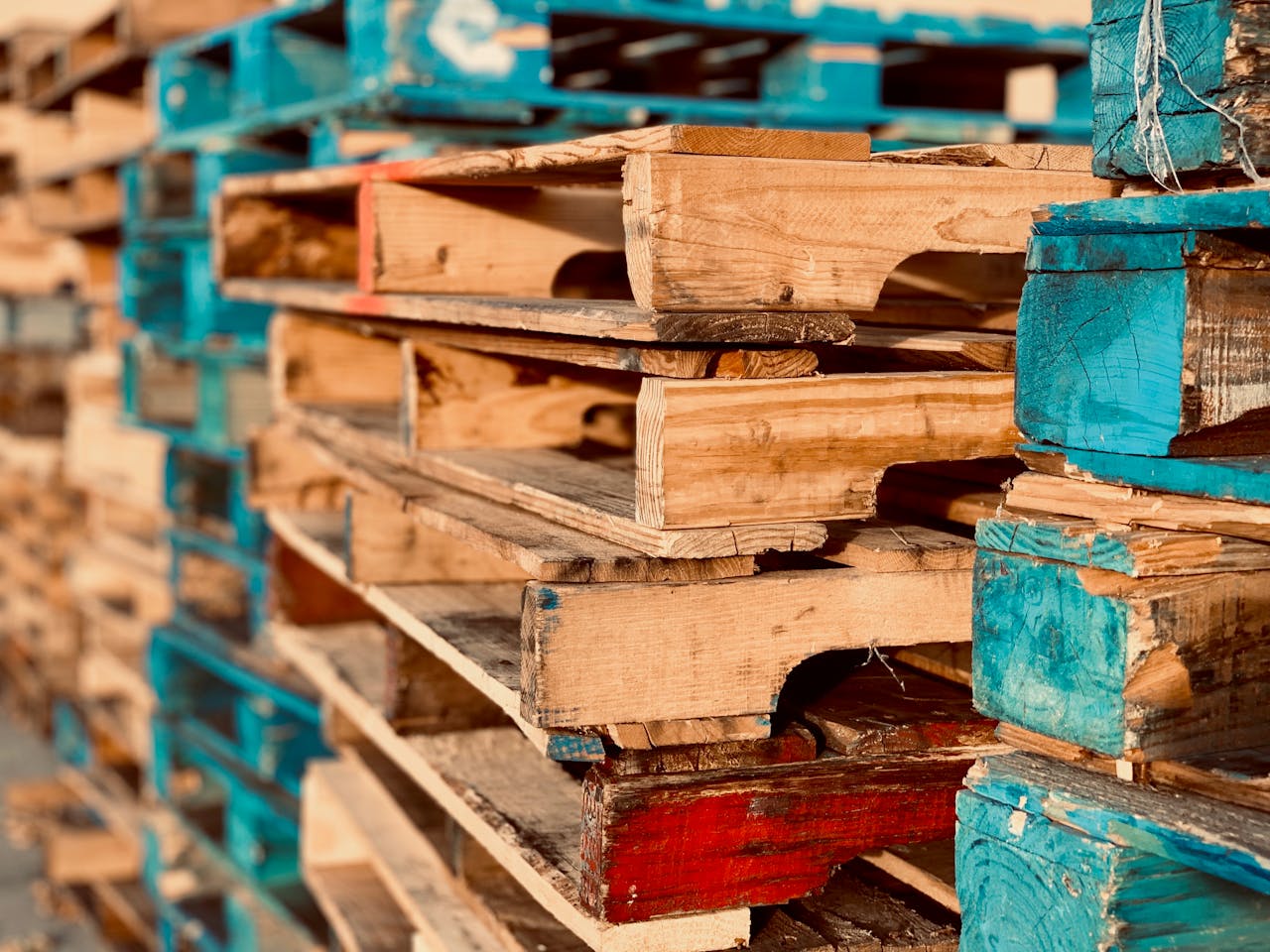 Oferta Close-up of colorful stacked wooden pallets in outdoor sunlight.